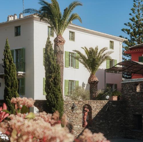 厄尔巴隆加Demeure Castel Brando Hôtel & Spa的前面有棕榈树的房子