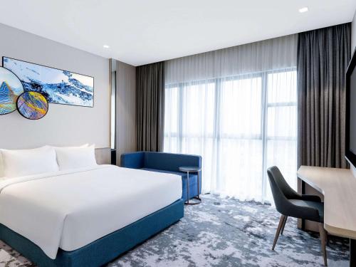 吉隆坡Mercure Kuala Lumpur Trion的酒店客房设有白色的床、书桌和窗户。