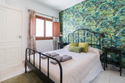 大加那利岛拉斯帕尔马斯El Rincón de los Artistas的一间卧室配有一张带热带壁纸的床