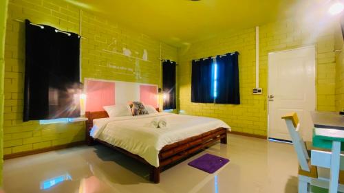 Ban Phang Khwang Taiพิมานอินทร์ รีสอร์ท的黄色客房内的一间卧室配有一张大床