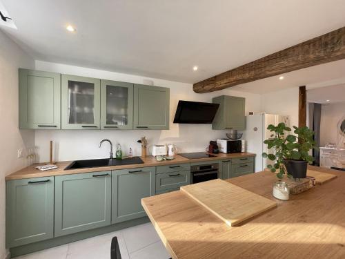 沙布利L'Authentique的厨房配有绿色橱柜和木桌