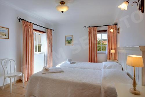卢斯Jardim Secreto的白色卧室配有两张床和椅子