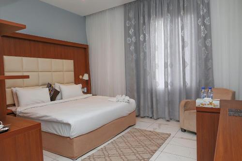 阿克拉San Marino Hotel的配有一张床和一把椅子的酒店客房