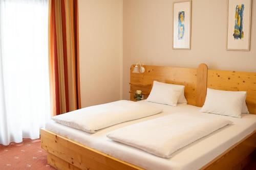 费尔德基兴费西格尔旅馆的一间卧室配有一张带白色床单的木床