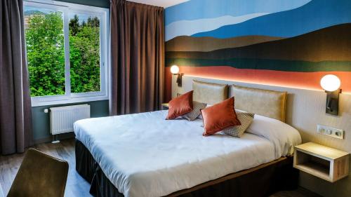 卢尔德清静酒店的酒店客房设有一张床,墙上挂有绘画作品