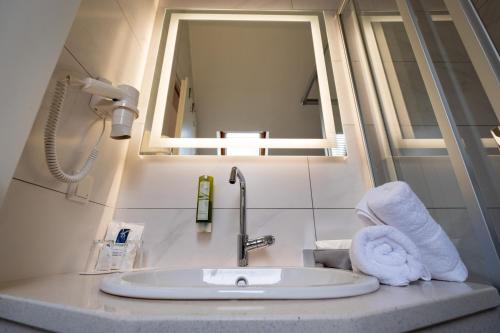 普劳西Landhotel Rose am Plauer See garni的浴室水槽配有镜子和毛巾