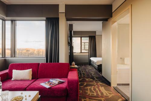 海牙巴比伦海牙酒店 的一间带红色沙发的客厅和一间卧室