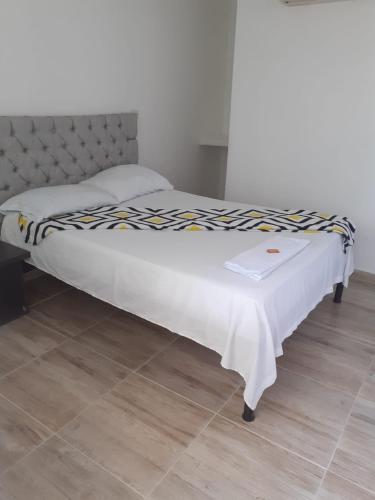 巴耶杜帕尔caribepremiumvalledupar的卧室内的一张床铺,上面有白色的毯子