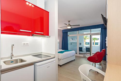卡门港全景公寓酒店 - 仅限成人入住的一间带红色橱柜的厨房和一间带一张床的卧室