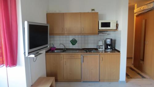 SchöfwegArberblick - b45689的厨房配有木制橱柜、电视和微波炉