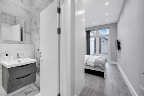 伦敦Your Cosy Stay Modern 3 Double Bedroom Apartment - Fully Furnished - 5 Mins walk to Stn的白色的浴室设有水槽和一张床