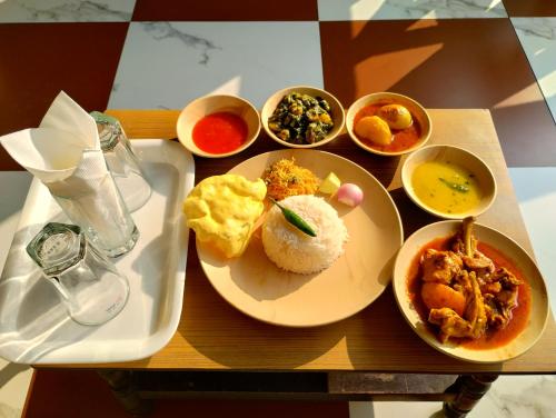 博尔普尔Muktomon Hotel & Resort的餐桌,盘子上放着食物和碗