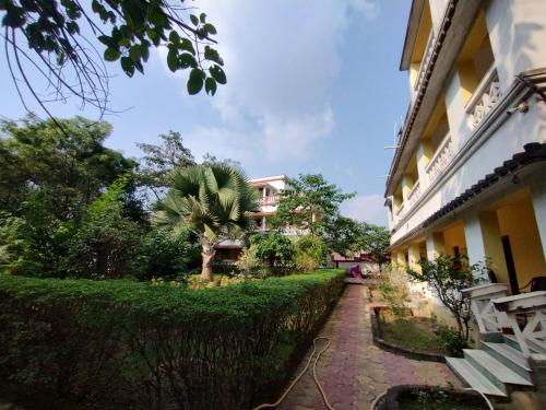 博尔普尔Muktomon Hotel & Resort的棕榈树建筑旁的走道