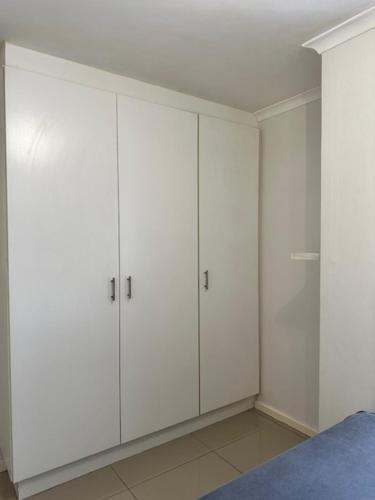 开普敦Cozy Rondebosch Apartment的白色卧室配有白色橱柜和1张床