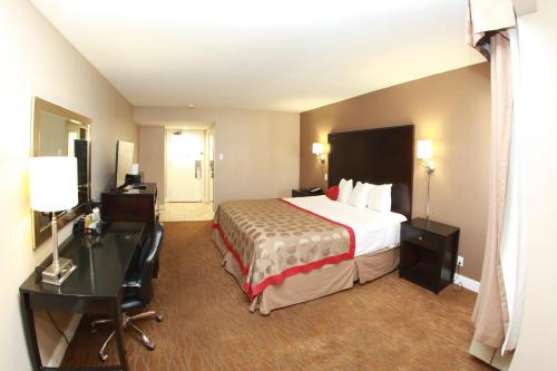 弗雷斯诺弗雷斯诺大学华美达酒店的配有一张床和一张书桌的酒店客房