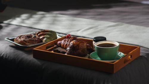 提华纳Hotel Brecha的床上的糕点盘和咖啡