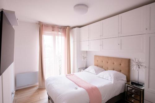 勒布尔热ELISE DE ROCHE Équipé Balcon Parking RER B的一间卧室配有一张带白色橱柜的床和窗户。