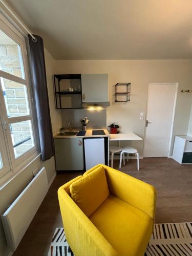 凯恩Appart du Théâtre的一间带黄色椅子的客厅和一间厨房