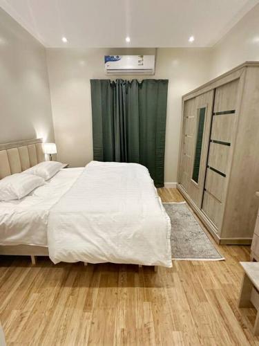 利雅德106 A شقة جميلة بغرفتين نوم ودخول ذاتي的卧室配有白色大床和绿色窗帘