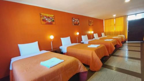 阿亚库乔Hotel Yañez Inn的橙色墙壁的房间的一排床位