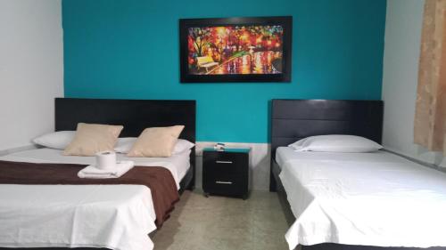 阿瓜奇卡HOTEL LUZ MERY的一间设有两张床的客房,墙上挂着一幅画