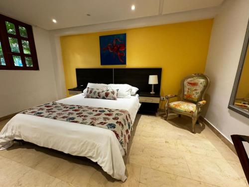 哥伦比亚港Porto Bello Hotel Boutique的一间卧室配有一张大床和一把椅子