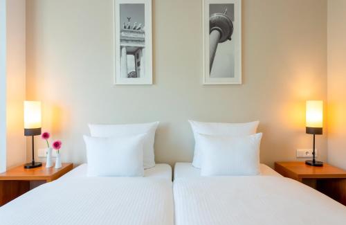 柏林Leonardo Hotel Berlin KU'DAMM的配有两盏灯的房间,设有两张白色的床