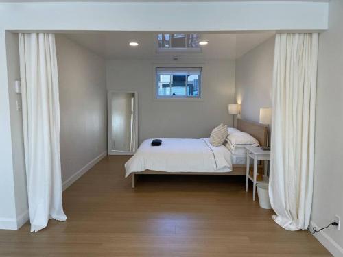 魁北克市Le Citadin - Maison neuve moderne & ensoleillée的一间卧室配有一张带白色床单的床和一扇窗户。