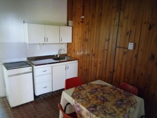 波萨达斯Lavalle hostel的厨房配有白色橱柜和桌椅