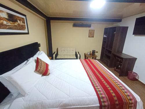 库斯科La Posada del Viajero的卧室配有一张白色大床和一把椅子