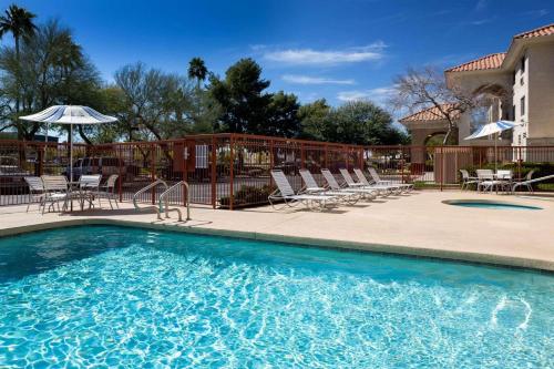 凤凰城卡尔森江山旅馆 - 凤凰城机场的一个带椅子和遮阳伞的游泳池