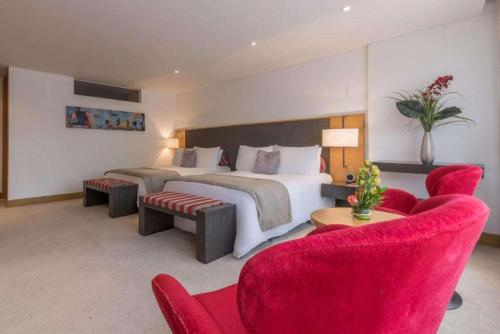 波哥大Faranda Collection Bogota, a member of Radisson Individuals的一间卧室配有一张大床和红色椅子