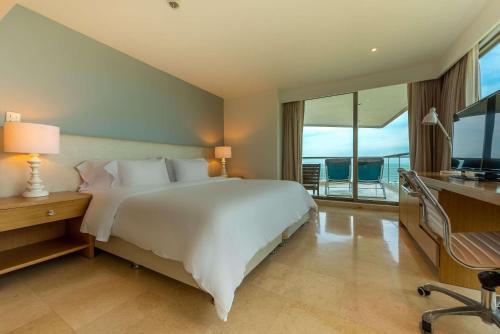 卡塔赫纳Radisson Cartagena Ocean Pavillion Hotel的卧室配有一张白色大床和电视。