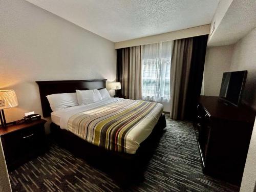 哥伦布Country Inn & Suites by Radisson, Columbus, GA的酒店客房,配有床和电视