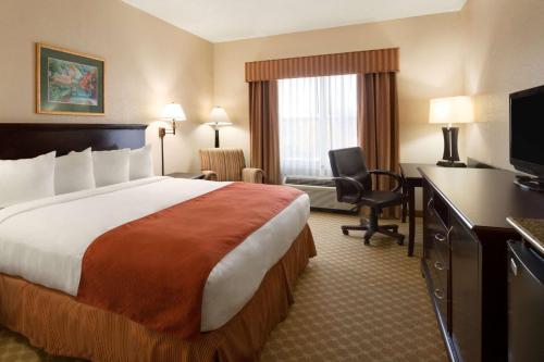 哥伦布Country Inn & Suites by Radisson, Columbus, GA的酒店客房设有一张大床和一张书桌。
