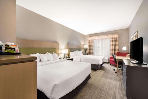 弗里波特Country Inn & Suites by Radisson, Freeport, IL的酒店客房设有两张床和电视。