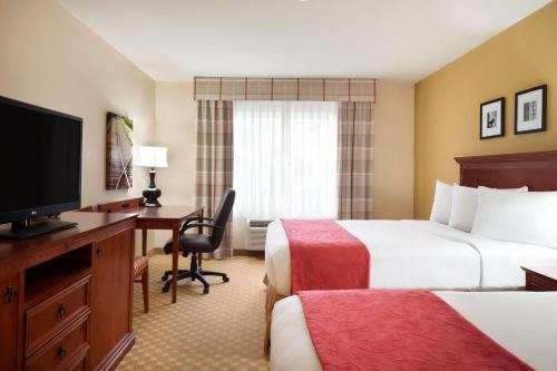 尚佩恩江山旅馆及套房 - 昌平诺斯的酒店客房设有两张床、一张桌子和一台电视。