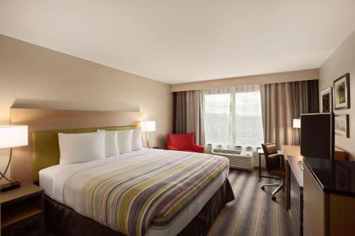 什里夫波特Country Inn & Suites by Radisson, Shreveport-Airport, LA的酒店客房,配有一张床和一张红色椅子