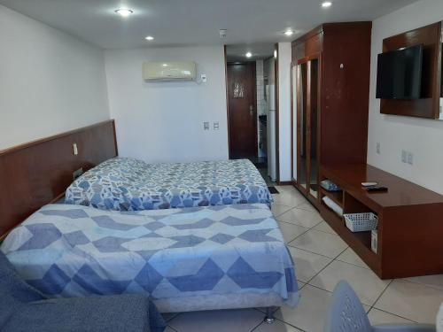 萨尔瓦多Flat no Sol Vitória Marina 2的一间卧室配有一张床、一张书桌和一台电视