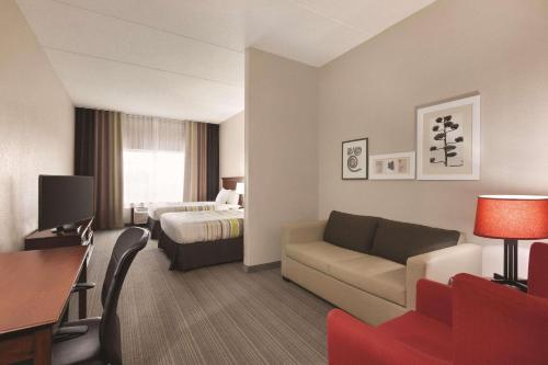 WillmarCountry Inn & Suites by Radisson, Willmar, MN的酒店客房设有一张沙发和一张床