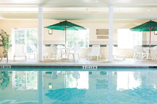 落基山卡尔森落基山乡村酒店及套房的一个带桌椅和遮阳伞的游泳池