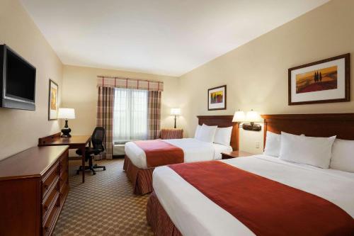 贝德福德曼彻斯特机场乡村套房酒店的酒店客房配有两张床和一张书桌