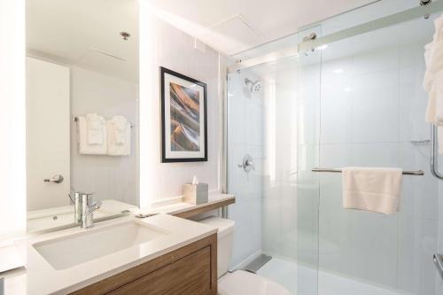 皇后区Radisson Hotel JFK Airport的白色的浴室设有水槽和淋浴。