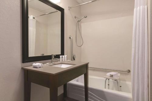 克林顿港克林顿港乡村套房酒店的浴室配有水槽和带镜子的浴缸