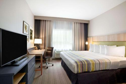 EnidCountry Inn & Suites by Radisson, Enid, OK的酒店客房配有一张床、一张书桌和一台电视。