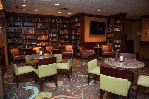 特里沃斯费城东北拉迪森酒店的图书馆配有2张桌子和椅子以及书架