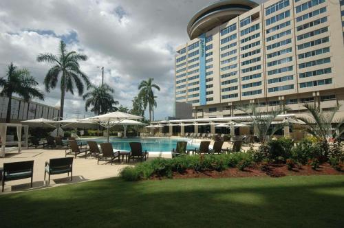 西班牙港特立尼达丽笙酒店的一个带游泳池和椅子的度假胜地和一座建筑