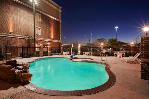 大学城学院站江山套房旅馆的一座游泳池,在晚上在建筑物前
