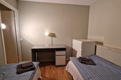 哥德堡Mysigt Stadsoas: En Modern lägenhet med 2 sovrum的客房设有两张床和一张带台灯的书桌。