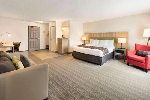 奇珀瓦福尔斯Country Inn & Suites by Radisson, Chippewa Falls, WI的酒店客房,配有一张床和一张红色椅子